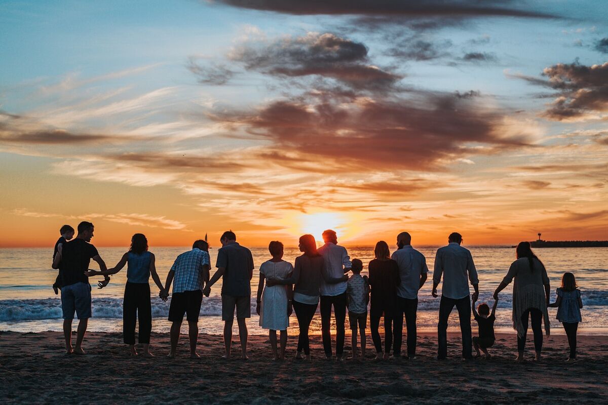 A multigenerational family together on the beach at sunset