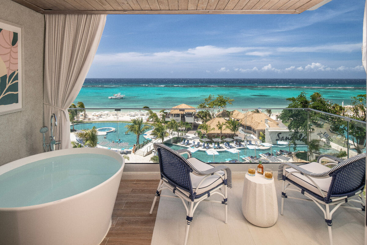 Sandals resort balcony with soaking tub overlooking turquoise Caribbean ocean and pool